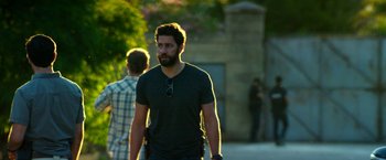 Movie still from “13 Hours” (2016), directed by Michael Bay – A man walking down the street with a gun in his hand; Medium shot, Over the shoulder angle