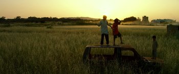 Movie still from “13 Hours” (2016), directed by Michael Bay – Two children standing on a bench in a grassy field; Wide shot, Low angle