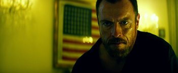 Movie still from “13 Hours” (2016), directed by Michael Bay – A person with a flag in the background; Close Up shot, Low angle