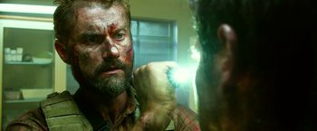 Movie still from “13 Hours” (2016), directed by Michael Bay – A man with bruises on his face is looking at himself in the mirror; Close Up shot, Over the shoulder angle