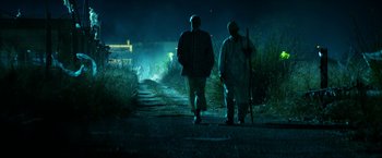 Movie still from “13 Hours” (2016), directed by Michael Bay – Two men walking down a dirt road at night; Wide shot, Low angle