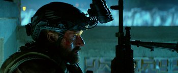 Movie still from “13 Hours” (2016), directed by Michael Bay – A person wearing a helmet and holding a rifle; Close Up shot, Over the shoulder angle