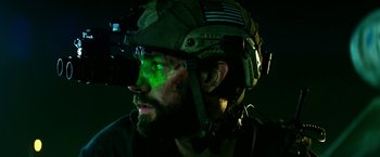 Movie still from “13 Hours” (2016), directed by Michael Bay – A man wearing a helmet with a green light on it's forehead; Close Up shot, Over the shoulder angle