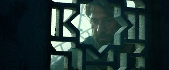 Movie still from “13 Hours” (2016), directed by Michael Bay – A man looking through a window in a building; Close Up shot, Low angle