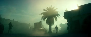 Movie still from “13 Hours” (2016), directed by Michael Bay – A man walking down a street near a palm tree; Extreme Wide shot, Low angle