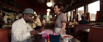 Movie still from “2 Guns” (2013), directed by Baltasar Kormákur – A woman standing at a counter in front of a man; Medium shot, Over the shoulder angle