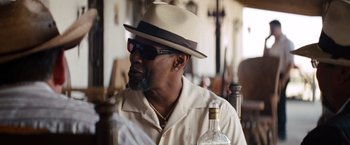 Movie still from “2 Guns” (2013), directed by Baltasar Kormákur – A man in a hat and sunglasses holding a bottle of alcohol; Close Up shot, Over the shoulder angle