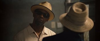 Movie still from “2 Guns” (2013), directed by Baltasar Kormákur – A man wearing a hat and sunglasses looking at the camera; Close Up shot, Over the shoulder angle