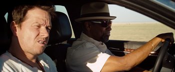 Movie still from “2 Guns” (2013), directed by Baltasar Kormákur – A man in a hat and sunglasses sitting in the driver's seat of a car; Close Up shot, Over the shoulder angle