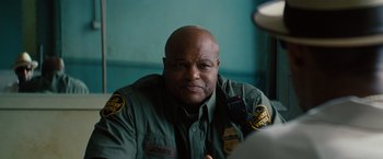 Movie still from “2 Guns” (2013), directed by Baltasar Kormákur – A police officer is sitting in front of a camera; Close Up shot, Over the shoulder angle