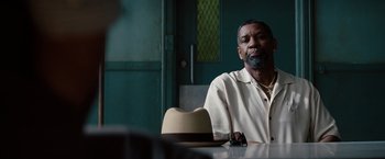 Movie still from “2 Guns” (2013), directed by Baltasar Kormákur – An older man sitting at a table with a hat; Close Up shot, Over the shoulder angle