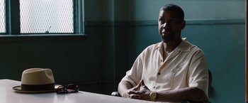 Movie still from “2 Guns” (2013), directed by Baltasar Kormákur – A man sitting at a table in front of a window; Medium shot, Over the shoulder angle