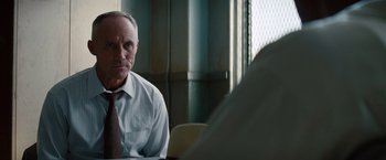 Movie still from “2 Guns” (2013), directed by Baltasar Kormákur – An older man sitting at a table in front of a window; Close Up shot, Over the shoulder angle