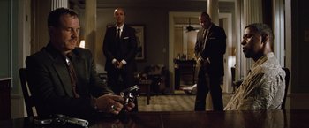 Movie still from “2 Guns” (2013), directed by Baltasar Kormákur – Three men in suits are standing in a living room; Medium shot, Over the shoulder angle