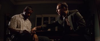 Movie still from “2 Guns” (2013), directed by Baltasar Kormákur – A man in a suit and tie is holding another man's hand; Medium shot, Low angle