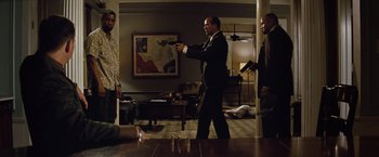 Movie still from “2 Guns” (2013), directed by Baltasar Kormákur – A man in a suit and tie holding a gun; Wide shot, Over the shoulder angle