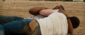 Movie still from “2 Guns” (2013), directed by Baltasar Kormákur – A man laying on the ground in the dirt; Medium shot, High angle