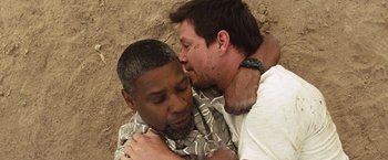 Movie still from “2 Guns” (2013), directed by Baltasar Kormákur – Two men laying on the ground and one of them is kissing the other on the cheek; Close Up shot, Overhead angle