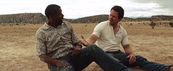 Movie still from “2 Guns” (2013), directed by Baltasar Kormákur – Two men sitting on the ground talking to each other; Medium shot, Over the shoulder angle