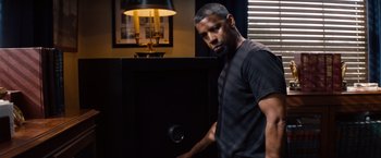 Movie still from “2 Guns” (2013), directed by Baltasar Kormákur – A man standing in front of a large black box; Medium shot, Low angle