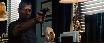 Movie still from “2 Guns” (2013), directed by Baltasar Kormákur – A man holding a gun in front of a lamp; Close Up shot, Low angle