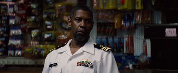 Movie still from “2 Guns” (2013), directed by Baltasar Kormákur – A man in a uniform is standing in front of a store; Close Up shot, Over the shoulder angle