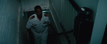 Movie still from “2 Guns” (2013), directed by Baltasar Kormákur – A man in uniform walking up a flight of stairs; Medium shot, Low angle