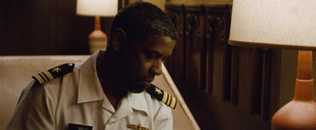 Movie still from “2 Guns” (2013), directed by Baltasar Kormákur – A man in a uniform sitting in front of a staircase; Close Up shot, Low angle