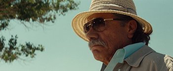 Movie still from “2 Guns” (2013), directed by Baltasar Kormákur – An older man wearing a straw hat and sunglasses; Close Up shot, Low angle