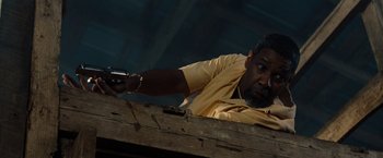 Movie still from “2 Guns” (2013), directed by Baltasar Kormákur – A man holding a gun while standing next to a wooden wall; Close Up shot, Low angle