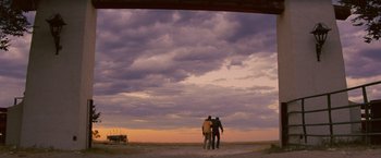 Movie still from “2 Guns” (2013), directed by Baltasar Kormákur – Two people standing on a dirt road under a cloudy sky; Extreme Wide shot, Low angle