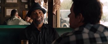 Movie still from “2 Guns” (2013), directed by Baltasar Kormákur – A man wearing a hat talking to another man; Close Up shot, Over the shoulder angle