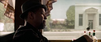 Movie still from “2 Guns” (2013), directed by Baltasar Kormákur – A man with a beard and a hat looking out a window; Close Up shot, Over the shoulder angle