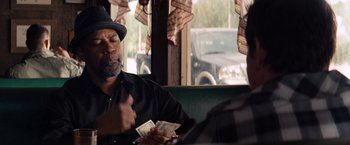 Movie still from “2 Guns” (2013), directed by Baltasar Kormákur – A man sitting at a table holding a stack of money; Close Up shot, Over the shoulder angle