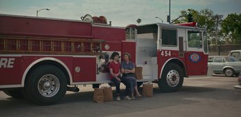 Movie still from “20th Century Women” (2016), directed by Mike Mills – Two women sitting on the back of a firetruck; Wide shot, Over the shoulder angle