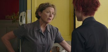 Movie still from “20th Century Women” (2016), directed by Mike Mills – An older woman standing in front of a yellow wall; Close Up shot, Over the shoulder angle