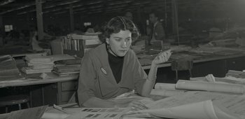 Movie still from “20th Century Women” (2016), directed by Mike Mills – A woman sitting at a table with papers in front of her; Medium shot, High angle