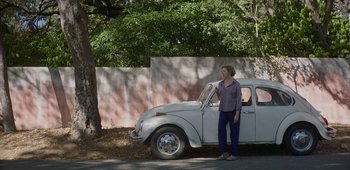 Movie still from “20th Century Women” (2016), directed by Mike Mills – A woman standing in front of a white car on the side of the road; Wide shot, Over the shoulder angle