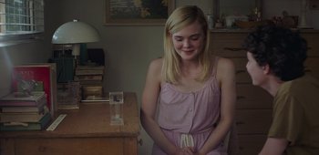 Movie still from “20th Century Women” (2016), directed by Mike Mills – A woman sitting in front of a wooden desk; Medium shot, Over the shoulder angle