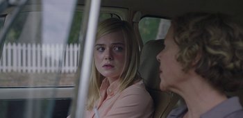 Movie still from “20th Century Women” (2016), directed by Mike Mills – A woman sitting in the back seat of a car with another woman; Close Up shot, Over the shoulder angle