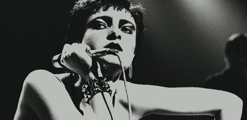 Movie still from “20th Century Women” (2016), directed by Mike Mills – A black - and - white photo of a person holding a microphone; Close Up shot, Low angle