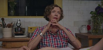 Movie still from “20th Century Women” (2016), directed by Mike Mills – A woman sitting at a table in front of papers; Close Up shot, Over the shoulder angle