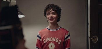 Movie still from “20th Century Women” (2016), directed by Mike Mills – A young man with a red shirt and black curly hair; Close Up shot, Over the shoulder angle
