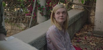 Movie still from “20th Century Women” (2016), directed by Mike Mills – A young woman sitting on a ledge in front of a tree; Medium shot, Over the shoulder angle