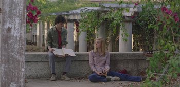 Movie still from “20th Century Women” (2016), directed by Mike Mills – A man and a woman sitting next to each other on the ground; Medium shot, Over the shoulder angle