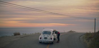 Movie still from “20th Century Women” (2016), directed by Mike Mills – A woman looking at a car on the side of the road; Extreme Wide shot, High angle