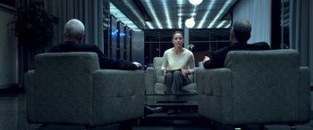 Movie still from “3 Days to Kill” (2014), directed by McG – A woman sitting on a chair in a room with three people; Wide shot, Over the shoulder angle