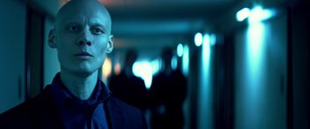 Movie still from “3 Days to Kill” (2014), directed by McG – A bald man in a blue shirt and jacket; Close Up shot, Low angle
