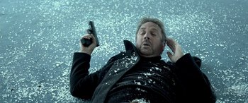 Movie still from “3 Days to Kill” (2014), directed by McG – A man laying on the ground holding a cell phone; Close Up shot, Overhead angle