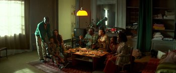 Movie still from “3 Days to Kill” (2014), directed by McG – A group of people sitting around a table eating food; Wide shot, High angle